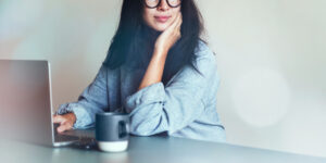 Mulher sentada em mesa com café na frente do computador